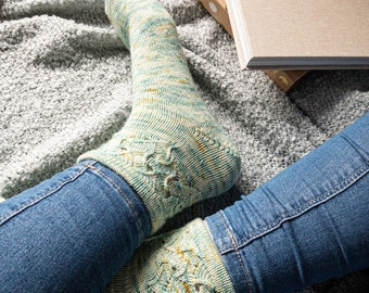 Peut inclure: Une paire de chaussettes à motifs bleu sarcelle et jaune avec un design en dentelle. Les chaussettes sont portées par une personne portant un jean bleu.