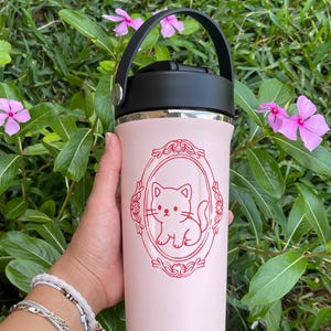 May include: A set of three ceramic mugs with a speckled, cream-colored glaze. Each mug features a different hand-painted floral design in shades of blue, green, and yellow. The mugs have a simple, modern shape.