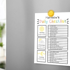 May include: A white daily checklist for Matthew, held by a yellow magnet on a gray refrigerator. The checklist includes morning, afternoon, and evening tasks, with colorful illustrations of a sun, cloud, and moon.