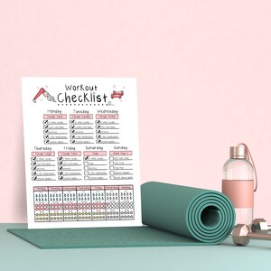 Op de afbeelding: Een workout checklist met een roze en wit ontwerp, met secties voor elke dag van de week. Een opgerolde teal yogamat, een doorzichtige waterfles met een roze hoes en twee zilveren dumbbells staan ook in de afbeelding.