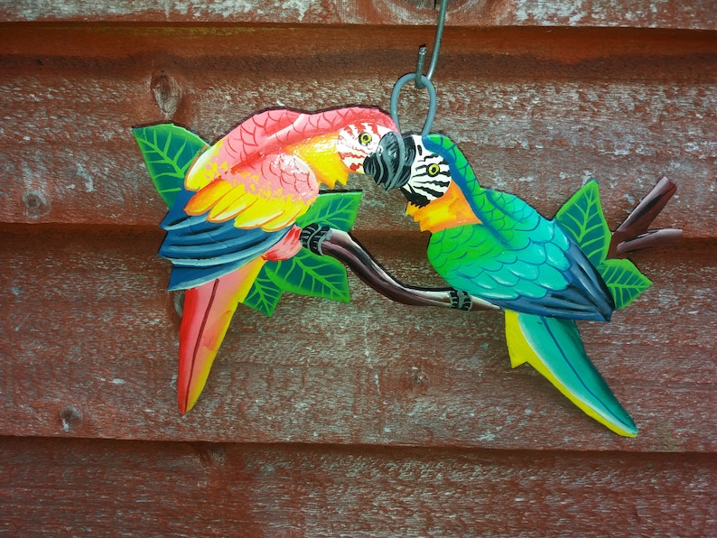Parrot wall art handmade in Haiti from old oil drums. There is a hook on the back to allow these beautiful birds to be hung on any wall, gate, fence or door. Hand painted by Haitian artists. These colourful metal birds make a great housewarming gift