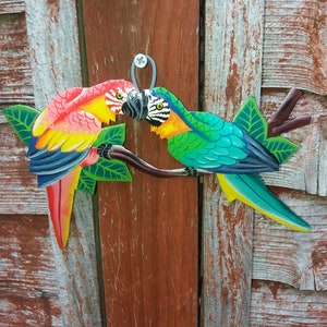 Parrot wall art handmade in Haiti from old oil drums. There is a hook on the back to allow these beautiful birds to be hung on any wall, gate, fence or door. Hand painted by Haitian artists. These colourful metal birds make a great housewarming gift