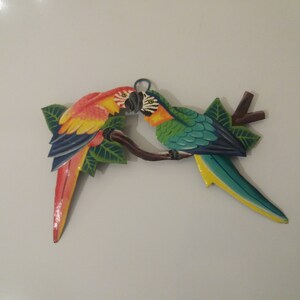 Parrot wall art handmade in Haiti from old oil drums. There is a hook on the back to allow these beautiful birds to be hung on any wall, gate, fence or door. Hand painted by Haitian artists. These colourful metal birds make a great housewarming gift