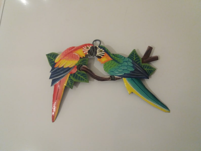 Parrot wall art handmade in Haiti from old oil drums. There is a hook on the back to allow these beautiful birds to be hung on any wall, gate, fence or door. Hand painted by Haitian artists. These colourful metal birds make a great housewarming gift