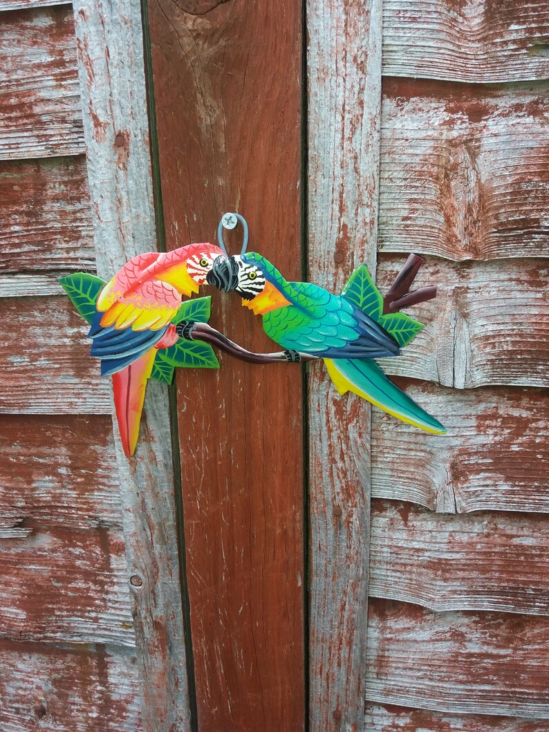 Parrot wall art handmade in Haiti from old oil drums. There is a hook on the back to allow these beautiful birds to be hung on any wall, gate, fence or door. Hand painted by Haitian artists. These colourful metal birds make a great housewarming gift