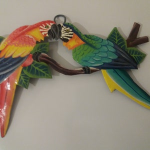 Parrot wall art handmade in Haiti from old oil drums. There is a hook on the back to allow these beautiful birds to be hung on any wall, gate, fence or door. Hand painted by Haitian artists. These colourful metal birds make a great housewarming gift