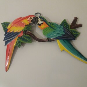 Parrot wall art handmade in Haiti from old oil drums. There is a hook on the back to allow these beautiful birds to be hung on any wall, gate, fence or door. Hand painted by Haitian artists. These colourful metal birds make a great housewarming gift