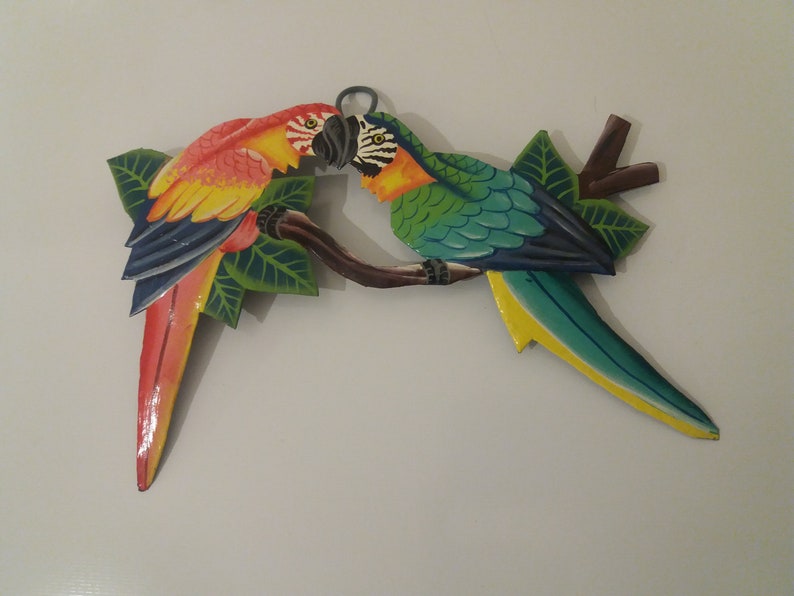 Parrot wall art handmade in Haiti from old oil drums. There is a hook on the back to allow these beautiful birds to be hung on any wall, gate, fence or door. Hand painted by Haitian artists. These colourful metal birds make a great housewarming gift