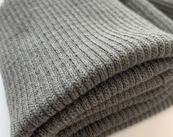 May include: A close-up of a folded gray ribbed knit fabric. The fabric is soft and textured, with a subtle sheen.