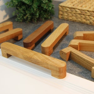 Op de afbeelding: Een set van acht houten ladegrepen in verschillende maten en vormen. De grepen zijn gemaakt van natuurlijk hout en hebben een rustieke, handgemaakte uitstraling.