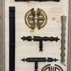 May include: A collection of antique-style door hardware, including latches, hinges, and a decorative circle. The hardware is displayed on a light wood background.