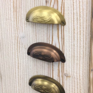 May include: Five cabinet knobs in different finishes: black, gold, copper, brass, and nickel. Each knob has a decorative floral design.