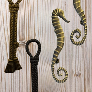 May include: Three decorative door handles in the shape of a seahorse and a rope. Two of the handles are gold and one is black.