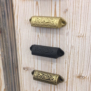 Puede incluir: Cinco tiradores de cajón ornamentados en diferentes acabados, incluyendo negro, latón y cobre. Los tiradores tienen todos el mismo diseño, con un patrón floral decorativo.