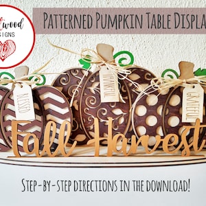 Puede incluir: Exhibición de mesa de otoño de madera con cuatro calabazas decoradas con diferentes patrones y las palabras "bendecido", "agradecido", "agradecido" y "otoño cosecha".