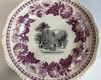 May include: A white ceramic plate with a purple floral design and a black and white image of a building in the center.