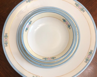 May include: A set of three white ceramic plates with blue and pink floral designs. The plates are nested together, with the smallest plate in the center.