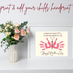 May include: A framed print with a pink butterfly made from handprints. The text reads "U make my heart flutter & give me wings to fly" and "Happy Mother's Day 2023".