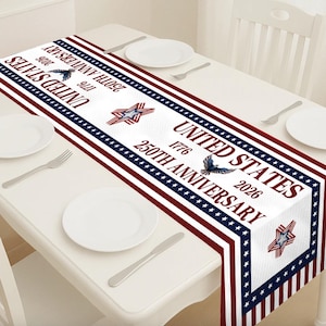 May include: A white table runner with a patriotic design. The runner features red, white, and blue stripes, stars, and text that reads "UNITED STATES 1776 250TH ANNIVERSARY 2026". Includes images of an eagle and a star.