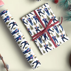 May include: White wrapping paper with a repeating pattern of a man in a blue suit and Christmas trees. A wrapped gift is tied with a burgundy ribbon. A roll of matching paper is next to the gift.