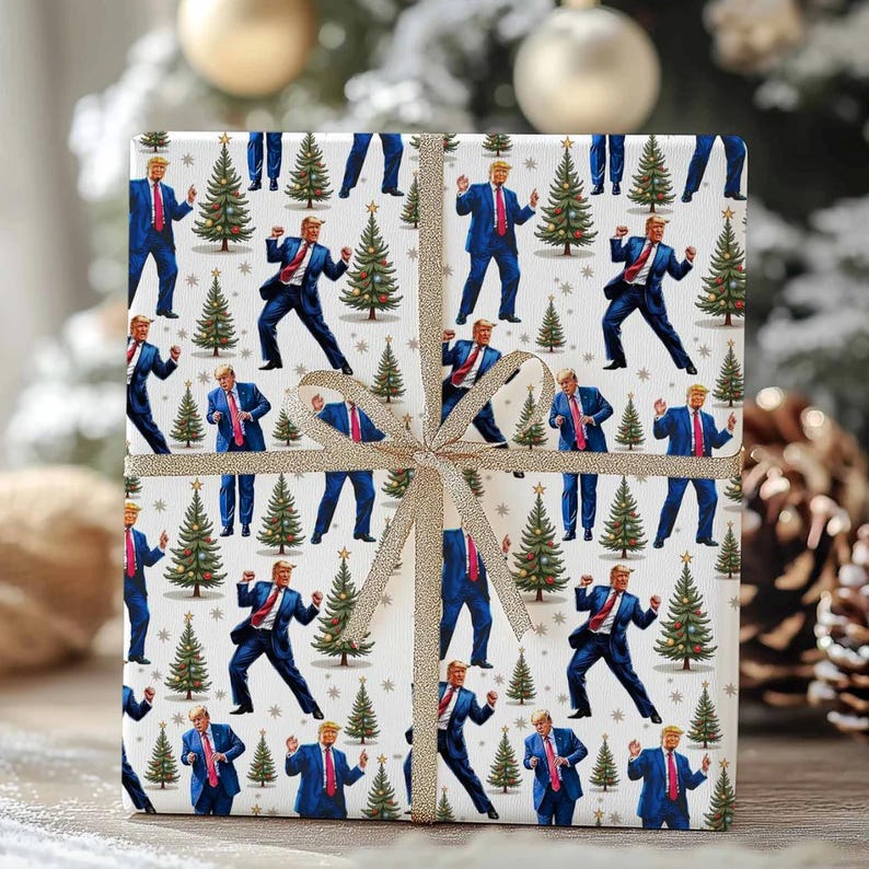 May include: A wrapped gift with a repeating pattern of a man in a blue suit and red tie dancing next to Christmas trees on a white background. The gift is tied with a gold ribbon.