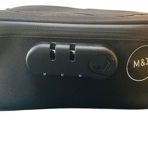 May include: Black rectangular storage case with a combination lock and the letters "M&J" printed on the side.