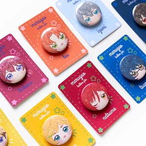 Könnte beinhalten: Eine Sammlung farbenfroher Anstecknadeln mit Illustrationen von Charakteren im Anime-Stil. Jede Anstecknadel wird auf einer passenden Karte mit dem Text "marugao button pin" und einem Charakternamen präsentiert. Die Anstecknadeln haben ein glänzendes Finish.