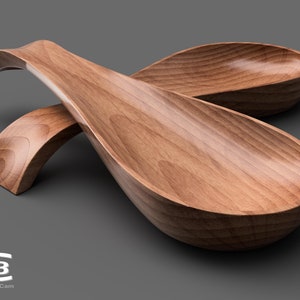 Peut inclure: Deux cuillères de service en bois, l'une posée sur l'autre, avec une poignée incurvée. Les cuillères sont en bois brun clair et ont une finition lisse et polie.