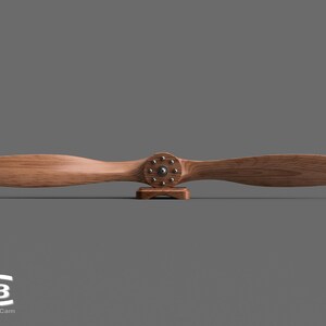 May include: A wooden airplane propeller with a brown finish and a metal hub with silver accents. The propeller is mounted on a small wooden stand.