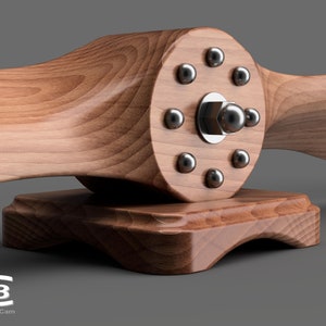 May include: A wooden airplane propeller with a silver metal hub and eight silver metal screws. The propeller is mounted on a wooden base.