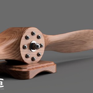 May include: A wooden airplane propeller with a metal hub and 10 screws. The propeller is mounted on a wooden base.