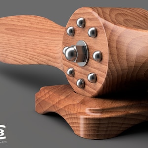 May include: A wooden airplane propeller with a silver metal hub and eight silver metal screws. The propeller is mounted on a wooden base.
