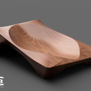 Op de afbeelding: Een houten serveerschaal met een gebogen, komvormig midden. De schaal is gemaakt van lichtbruin hout met een gladde, gepolijste afwerking.