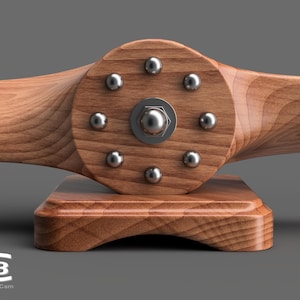 May include: A wooden airplane propeller with a circular base. The propeller has eight silver metal screws around the center hub.