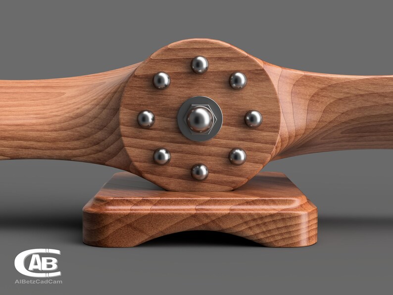 May include: A wooden airplane propeller with a circular base. The propeller has eight silver metal screws around the center hub.