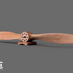 May include: A wooden airplane propeller with a metal hub and a wooden base. The propeller is mounted on the base and is ready to be displayed.