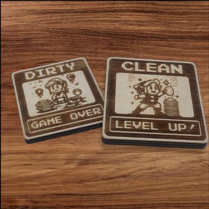May include: Two wooden coasters with a pixelated design. The first coaster says "DIRTY" and "GAME OVER" with a pixelated character. The second coaster says "CLEAN" and "LEVEL UP!" with a pixelated character.