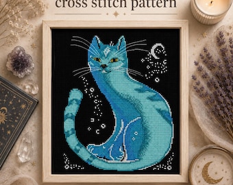 May include: A cross stitch pattern featuring a stylized blue cat on a black background. The cat has yellow eyes and a diamond mark on its forehead. The design includes small white stars and a crescent moon. The text "cross stitch pattern" and "PDF" appear.