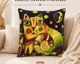 May include: A square throw pillow featuring a cross stitch pattern of a stylized cat in yellow, green, and red tones against a dark blue starry night sky with a crescent moon. The text CROSS STITCH PATTERN is visible above, and a PDF label is below.