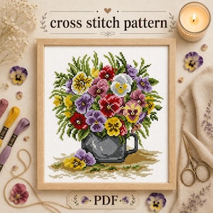 May include: A cross stitch pattern featuring a bouquet of colorful pansies in a dark gray mug. The design includes red, yellow, purple, and white flowers with green foliage. The text "cross stitch pattern" and "PDF" are visible on the page.