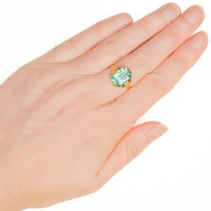 May include: A gold ring with a light green gemstone set in a bezel setting.