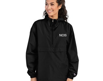 May include: Black hooded anorak jacket with a zipper closure and a front pocket. The jacket has the word "NCIS" embroidered on the front in white.