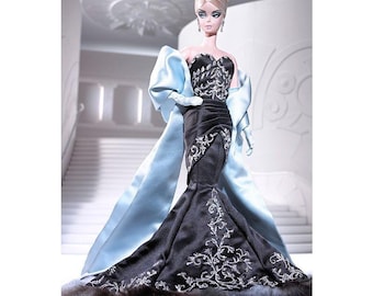 May include: A fashion doll in a black and silver evening gown with a fur trim. The doll has blonde hair styled in an updo, a tiara, and blue eye shadow. A light blue shawl is draped over the doll's shoulders.
