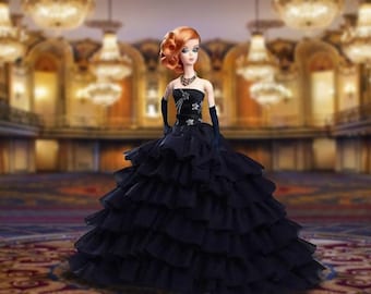 Puede incluir: Muñeca con un vestido negro sin tirantes con falda con volantes, guantes negros y un collar en forma de estrella. La muñeca tiene el pelo rojo y posa en un salón de baile con candelabros.