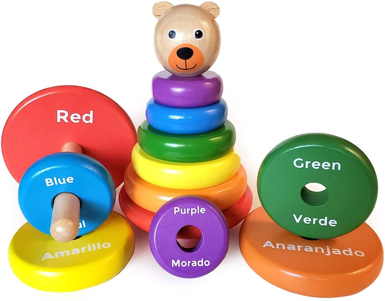 Puede incluir: Un juguete de apilar de madera con una cabeza de oso en la parte superior y anillos coloridos. Los anillos est&aacute;n etiquetados con los colores rojo, azul, amarillo, morado, verde y naranja.