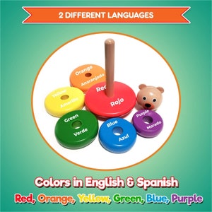 Puede incluir: Un juguete de apilar de madera con un oso en la parte superior y seis anillos coloridos. Los anillos est&aacute;n etiquetados con los colores en ingl&eacute;s y espa&ntilde;ol. Los colores son rojo, naranja, amarillo, verde, azul y morado.