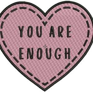 May include: Pink heart-shaped patch with black stitching and the text "YOU ARE ENOUGH" in black.