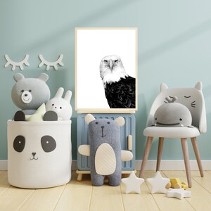 May include: A black and white photo of a bald eagle with a light blue background. The photo is framed and hanging on a wall in a child's room. There are stuffed animals and a chair in the room.