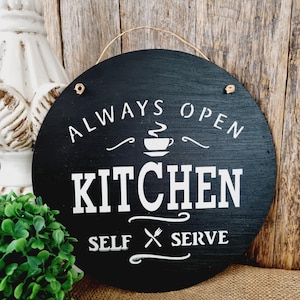 May include: Black and white round wooden sign with the text "Always Open Kitchen Self Serve" and a coffee cup icon.