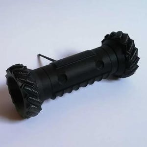 May include: A matte black cylindrical object featuring two large, textured wheels on either end. The central body has a ribbed, grooved surface with circular indentations and a single thin, straight antenna-like protrusion extending from the top.